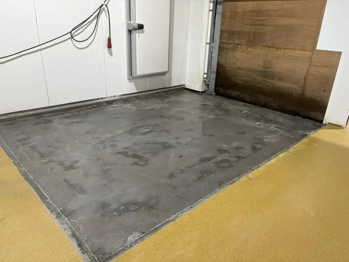 Sol gris préparé contre une paroi en panneaux, bordé d'un revêtement jaune