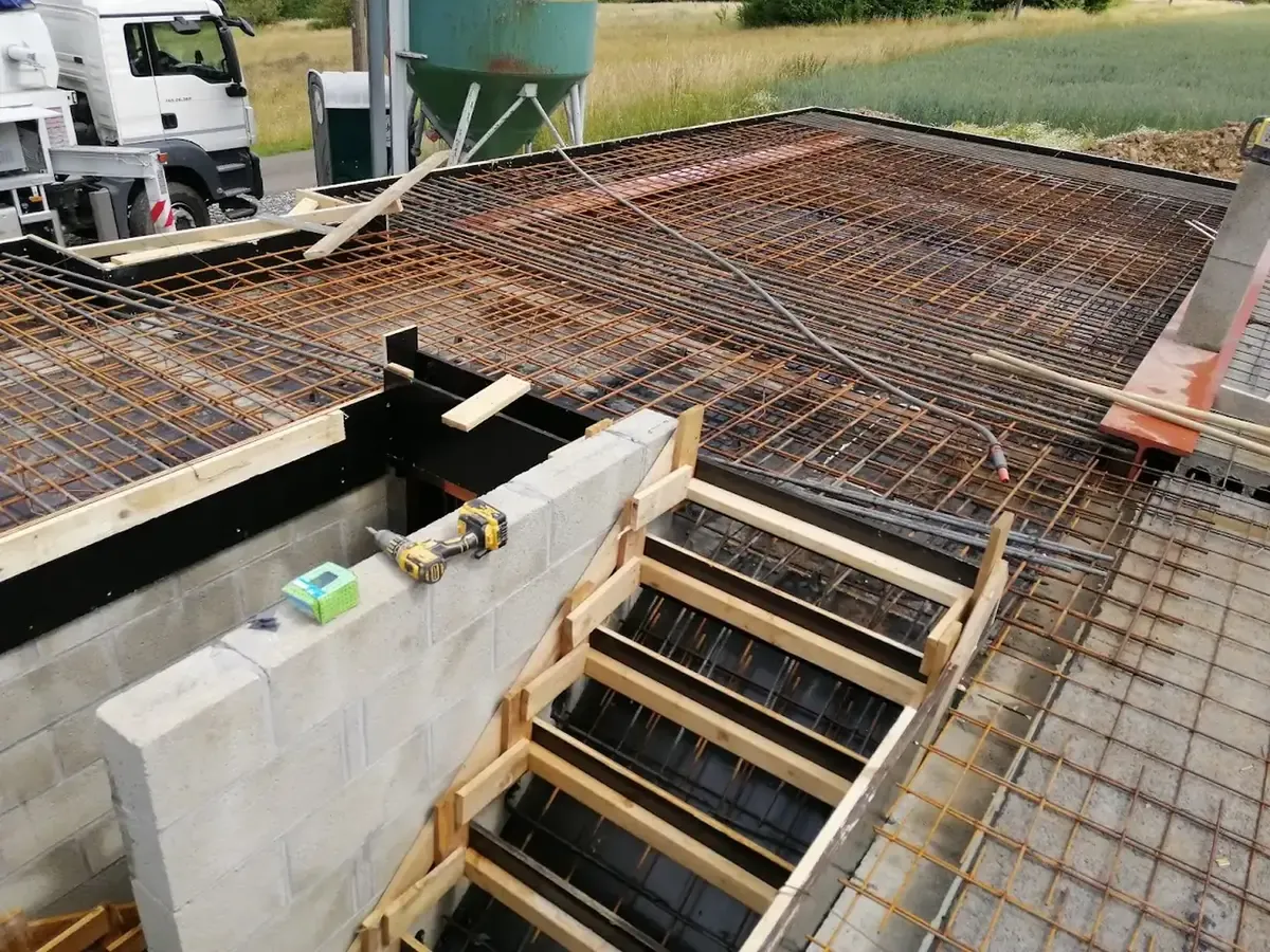 Armature d'acier et coffrage d'une dalle de béton avec escalier coffré, camion et silo en arrière-plan