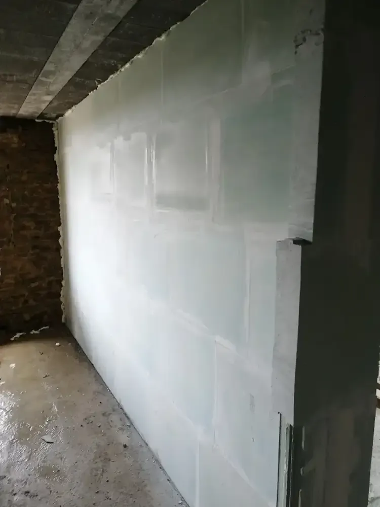 Mur en blocs de plâtre blanc monté dans une cave contre un mur ancien